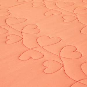 A heart pattern stitched in red thread on orange fabric